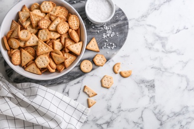 Photo of Delicious crispy crackers on white marble table, flat lay
