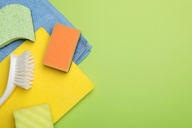 Flat lay composition with color sponges on green background. Space for text