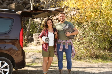 Photo of Couple of campers with sleeping bag and mat near car outdoors
