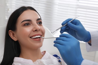 Dentist examining young woman's teeth in modern clinic