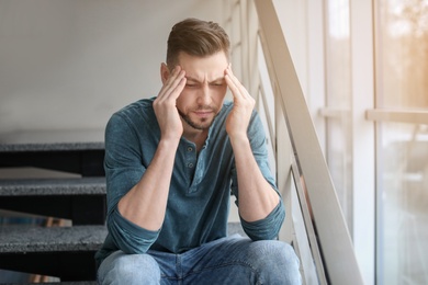 Man suffering from headache near window in office