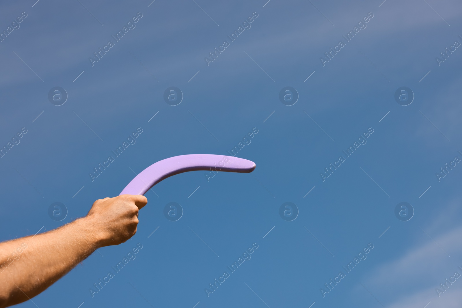 Photo of Man throwing boomerang against blue sky, closeup. Space for text