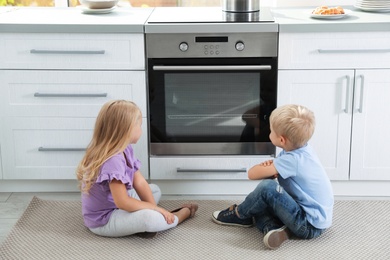 Little kids baking something in oven at home