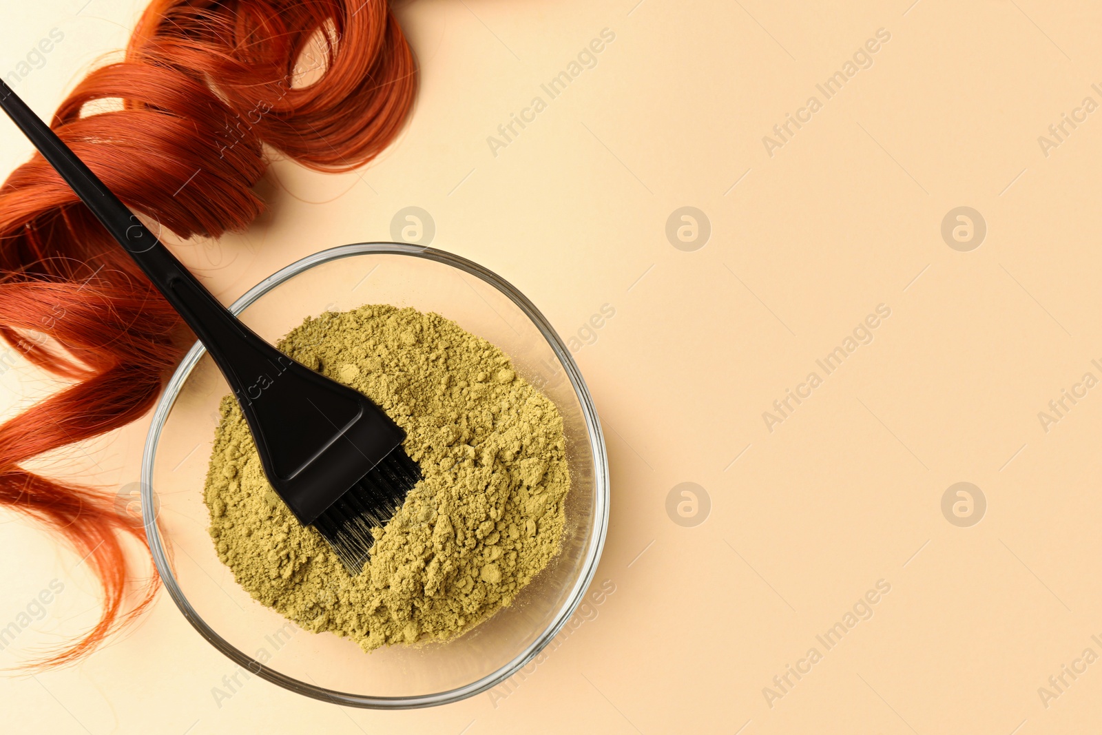 Photo of Bowl of henna powder, brush and red strand on beige background, flat lay with space for text. Natural hair coloring