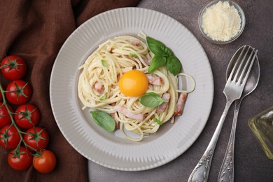 Photo of Delicious pasta Carbonara with egg yolk served on grey table, flat lay