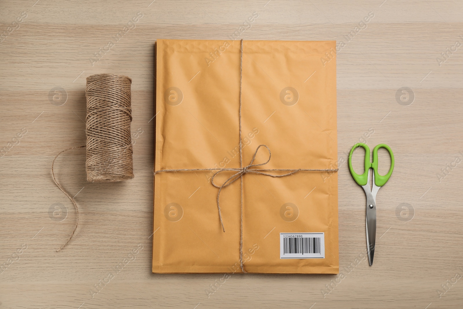 Photo of Padded envelope, rope and scissors on wooden background, flat lay