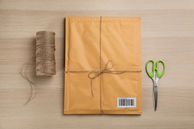 Photo of Padded envelope, rope and scissors on wooden background, flat lay