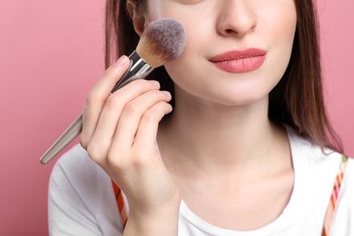 Photo of Beauty blogger doing make up on pink background, closeup