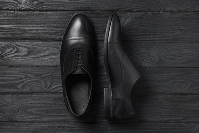 Photo of Pair of leather men shoes on black wooden background, top view