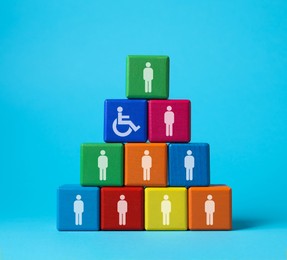 Image of Inclusive workplace culture. Pyramid of colorful cubes with human icons and one with international symbol of access on light blue background