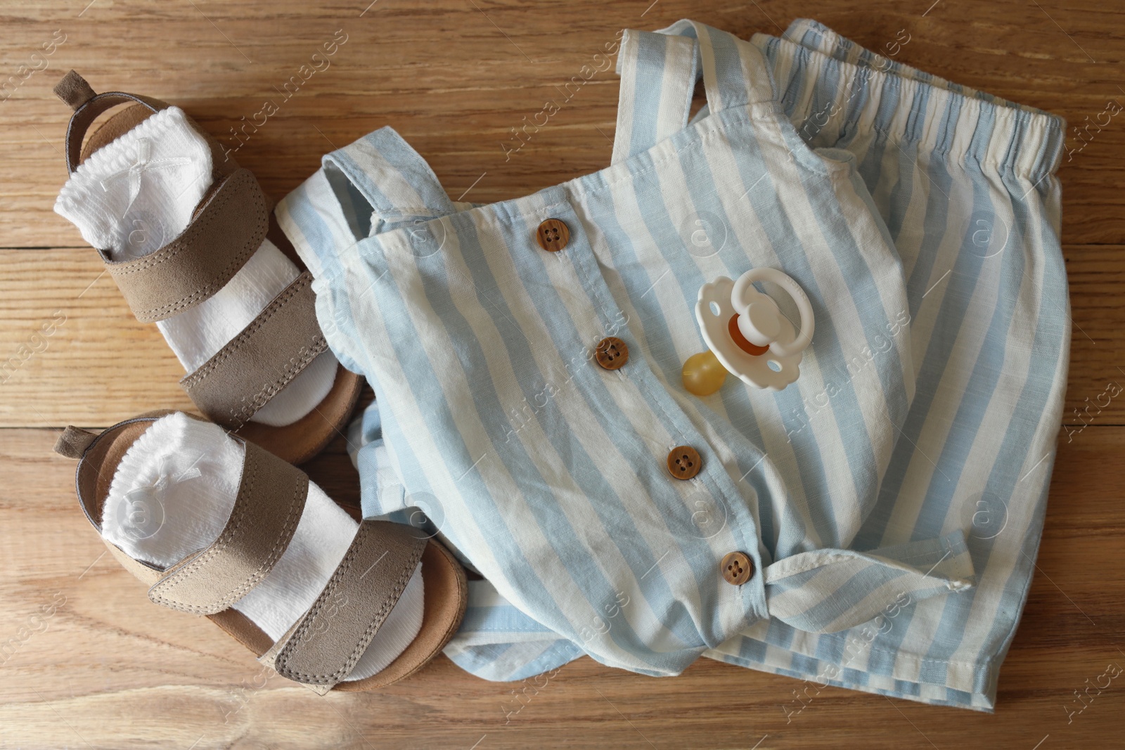 Photo of Stylish child clothes, shoes and accessories on wooden background, flat lay