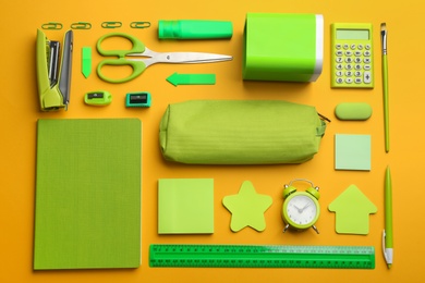 Photo of Flat lay composition with green school stationery on orange background. Back to school