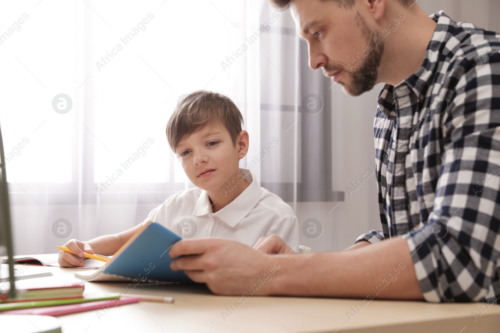 Photo of Dad helping his son with school assignment at home