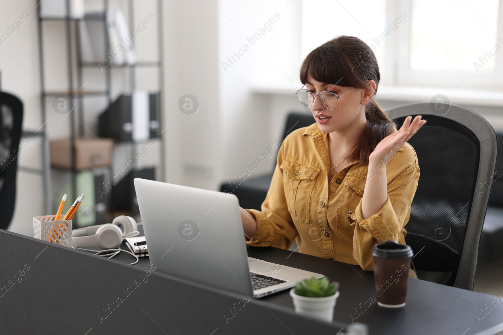 Photo of Woman using video chat during webinar at table in office