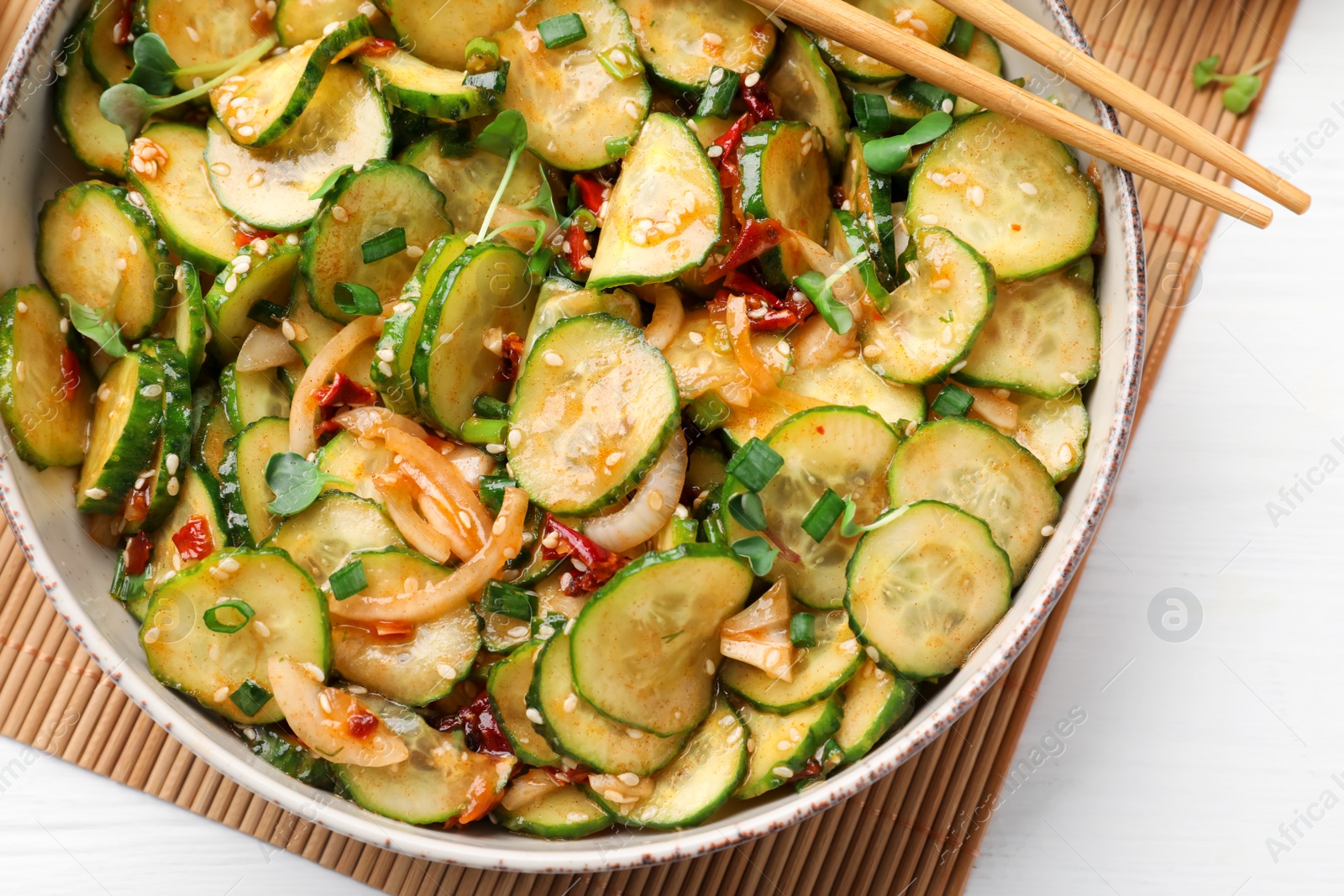 Photo of Bowl of delicious cucumber salad served on white wooden table, top view