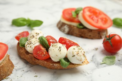 Photo of Delicious sandwiches with mozzarella, fresh tomatoes and basil on white marble table
