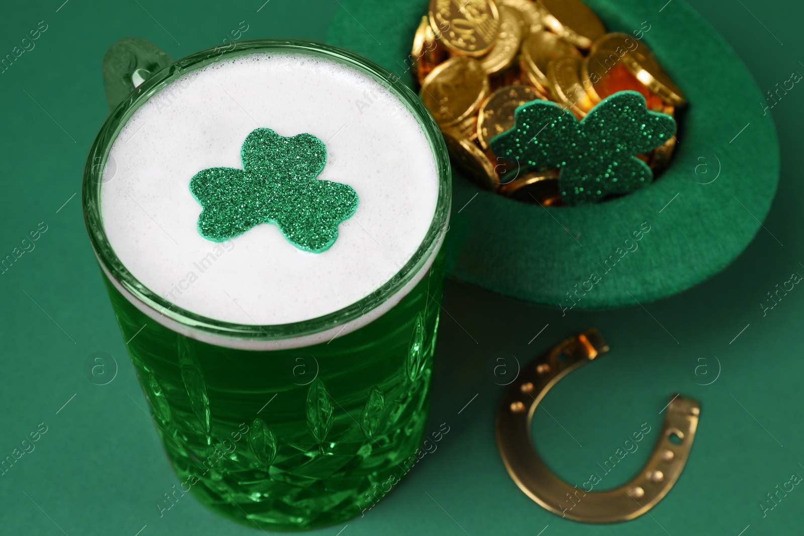 Photo of St. Patrick's day party. Green beer, leprechaun hat with gold, horseshoe and decorative clover leaves on green background