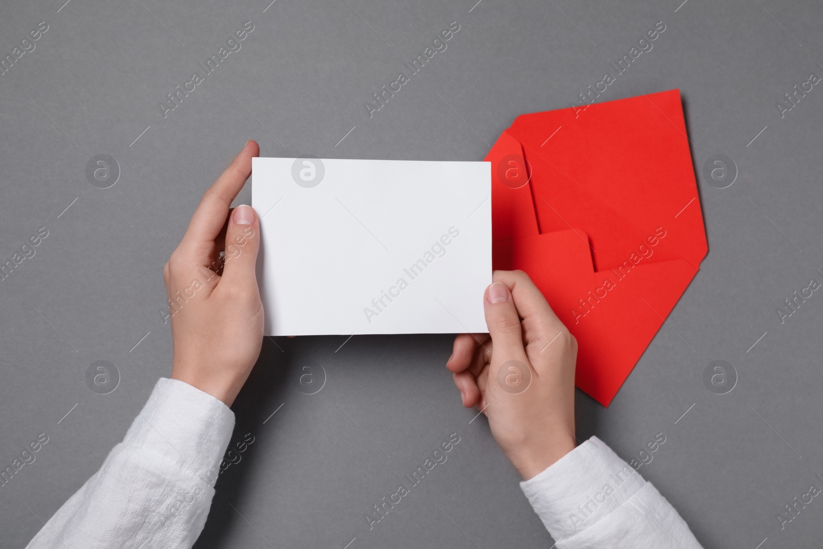 Photo of Woman with blank card at grey table, top view. Space for text