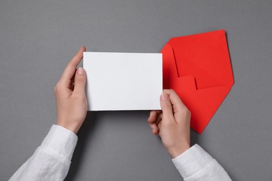 Photo of Woman with blank card at grey table, top view. Space for text