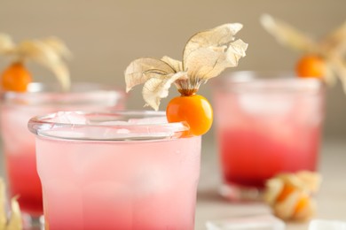 Photo of Refreshing cocktail decorated with physalis fruit on blurred background, closeup. Space for text