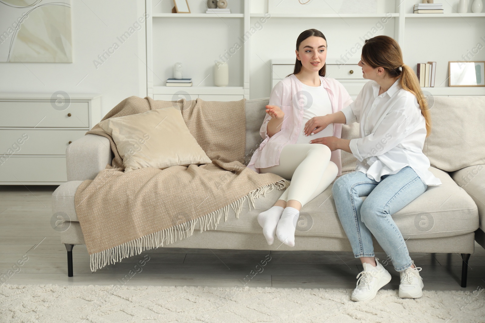 Photo of Doula taking care of pregnant woman on sofa at home. Preparation for child birth