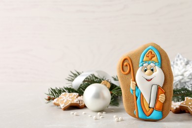 Photo of Tasty gingerbread cookie and festive decor on light table, space for text. St. Nicholas Day celebration