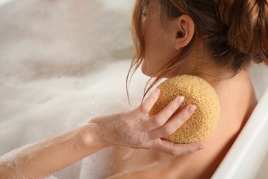Woman rubbing neck with sponge while taking bath, closeup