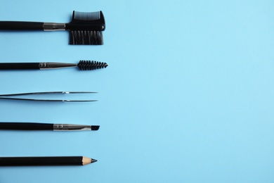 Set of professional eyebrow tools on blue background, flat lay. Space for text