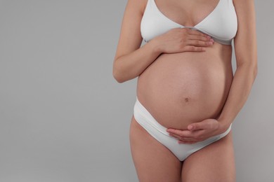 Photo of Pregnant woman in stylish comfortable underwear on grey background, closeup. Space for text