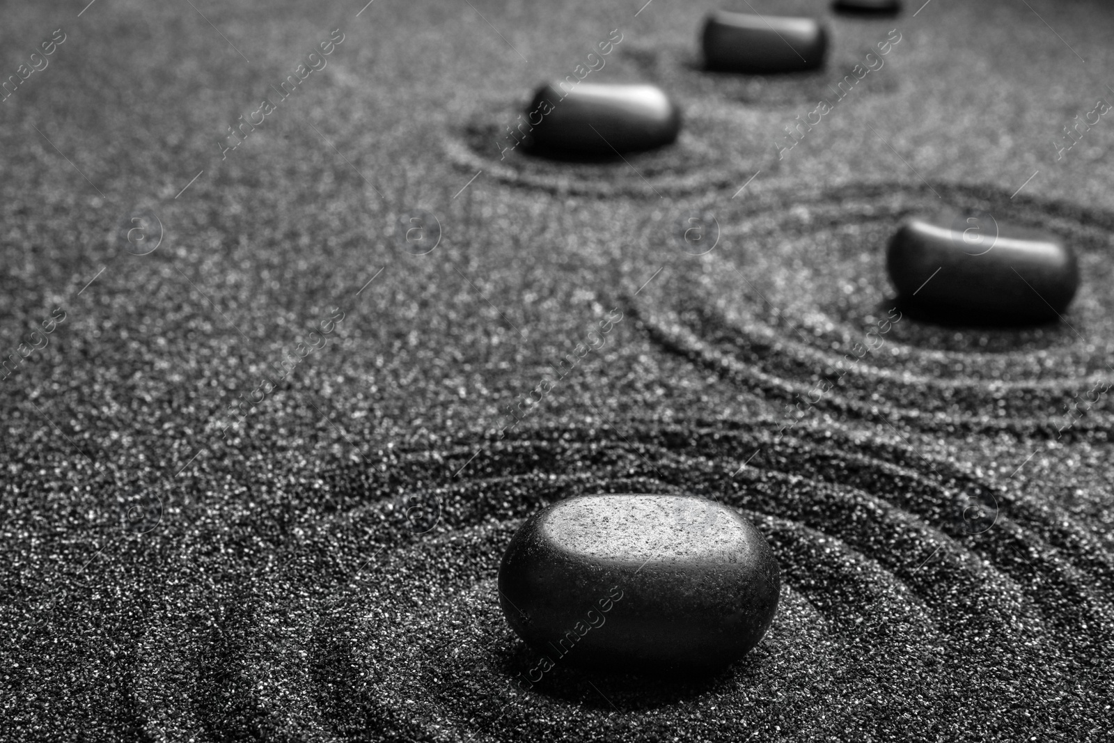 Photo of Black sand with stones and beautiful pattern. Zen concept