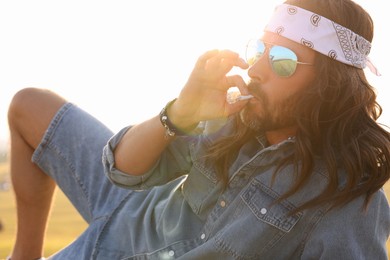 Hippie man in headband smoking joint outdoors