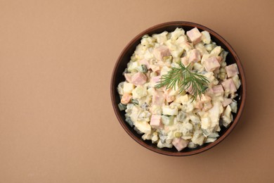 Tasty Olivier salad with boiled sausage in bowl on beige table, top view. Space for text