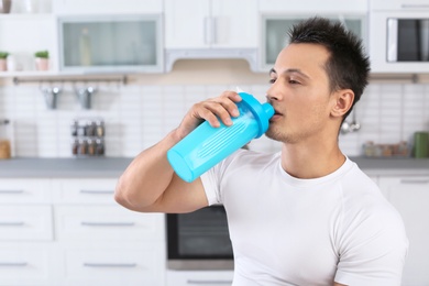 Photo of Young man drinking protein shake in kitchen