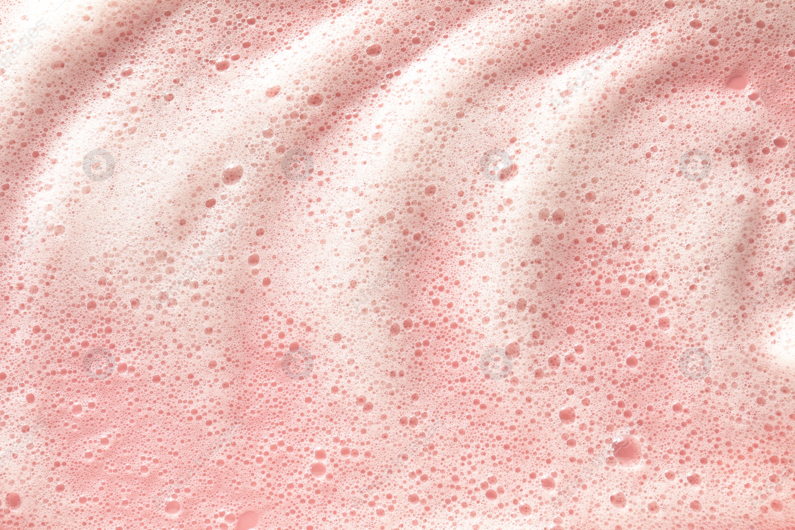 Photo of White washing foam on pale pink background, top view