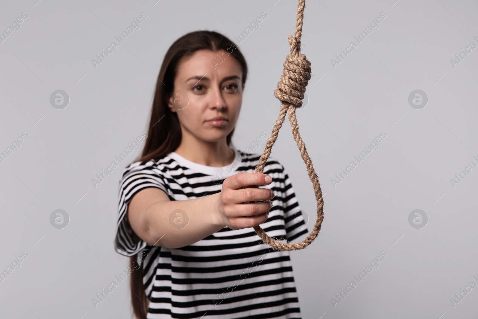 Photo of Depressed woman with rope noose on light grey background