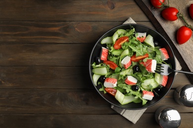 Photo of Delicious crab stick salad served on wooden table, flat lay. Space for text