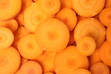 Slices of fresh ripe carrots as background, top view