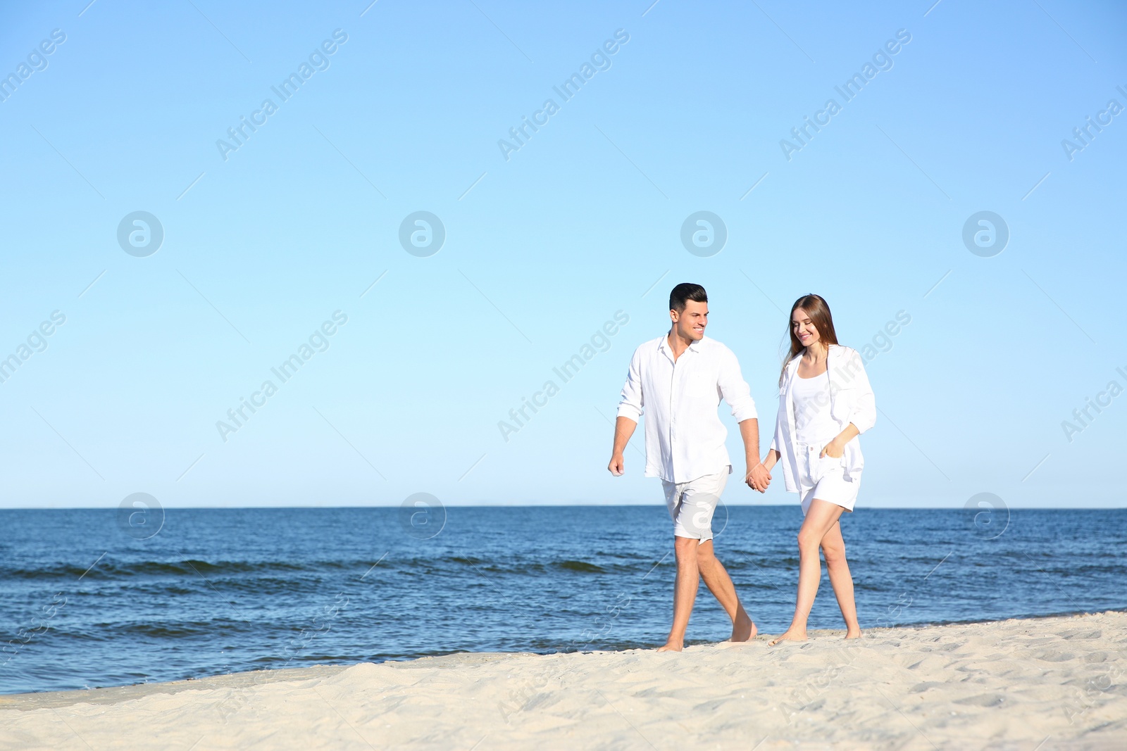 Photo of Lovely couple walking on beach. Space for text