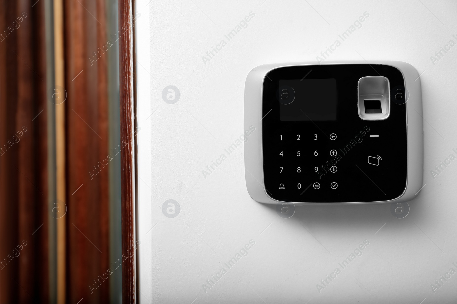 Photo of Modern alarm system with fingerprint scanner on white wall indoors. Space for text