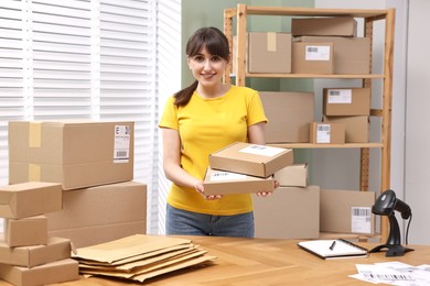 Photo of Parcel packing. Post office worker with parcels at wooden table indoors