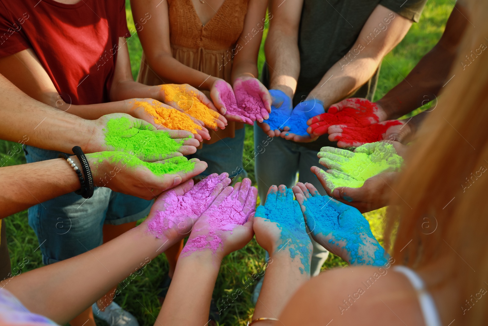 Photo of Friends with colorful powder dyes outdoors, closeup. Holi festival celebration