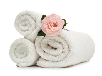 Photo of Clean rolled towels with flower on white background