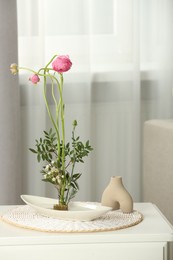 Photo of Ikebana art. Beautiful flowers and green branches carrying cozy atmosphere at home