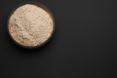 Photo of Bowl of brewer`s yeast flakes on black background, top view. Space for text