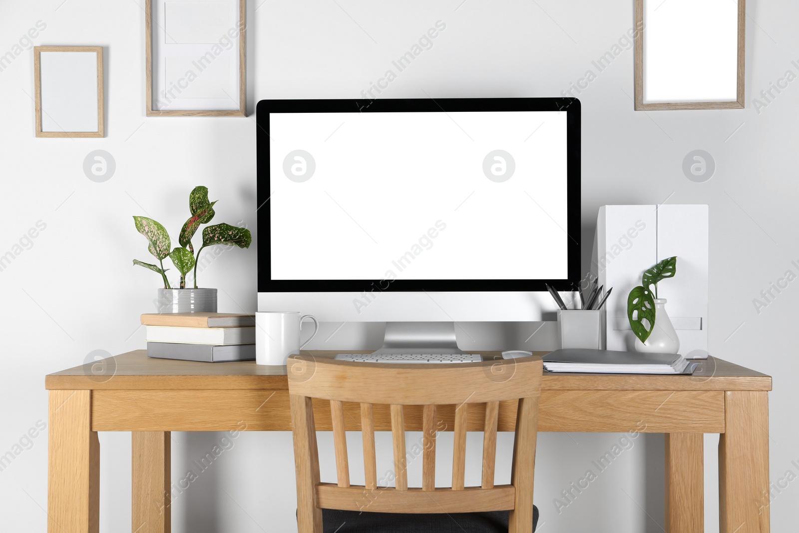 Photo of Home workplace. Computer, stationery and houseplants on wooden desk