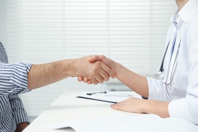 Photo of Doctor shaking hands with patient in hospital, closeup