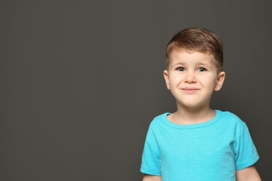 Portrait of cute little boy on dark background. Space for text