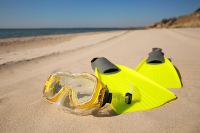Pair of flippers and diving mask on sandy beach