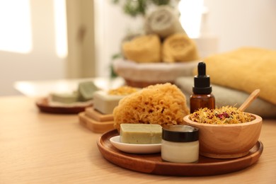 Photo of Dry flowers, loofah, soap bar, bottle of essential oil and jar with cream on wooden table indoors, space for text. Spa time