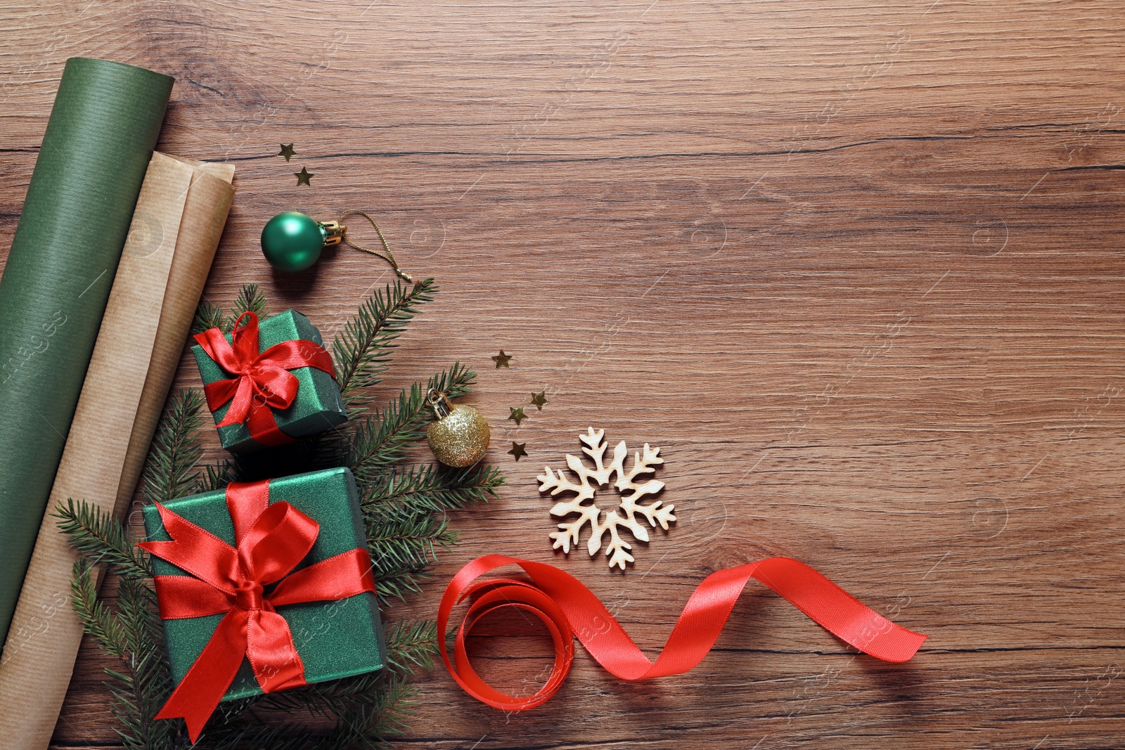 Photo of Flat lay composition with beautiful Christmas gift boxes and wrapping paper on wooden table. Space for text